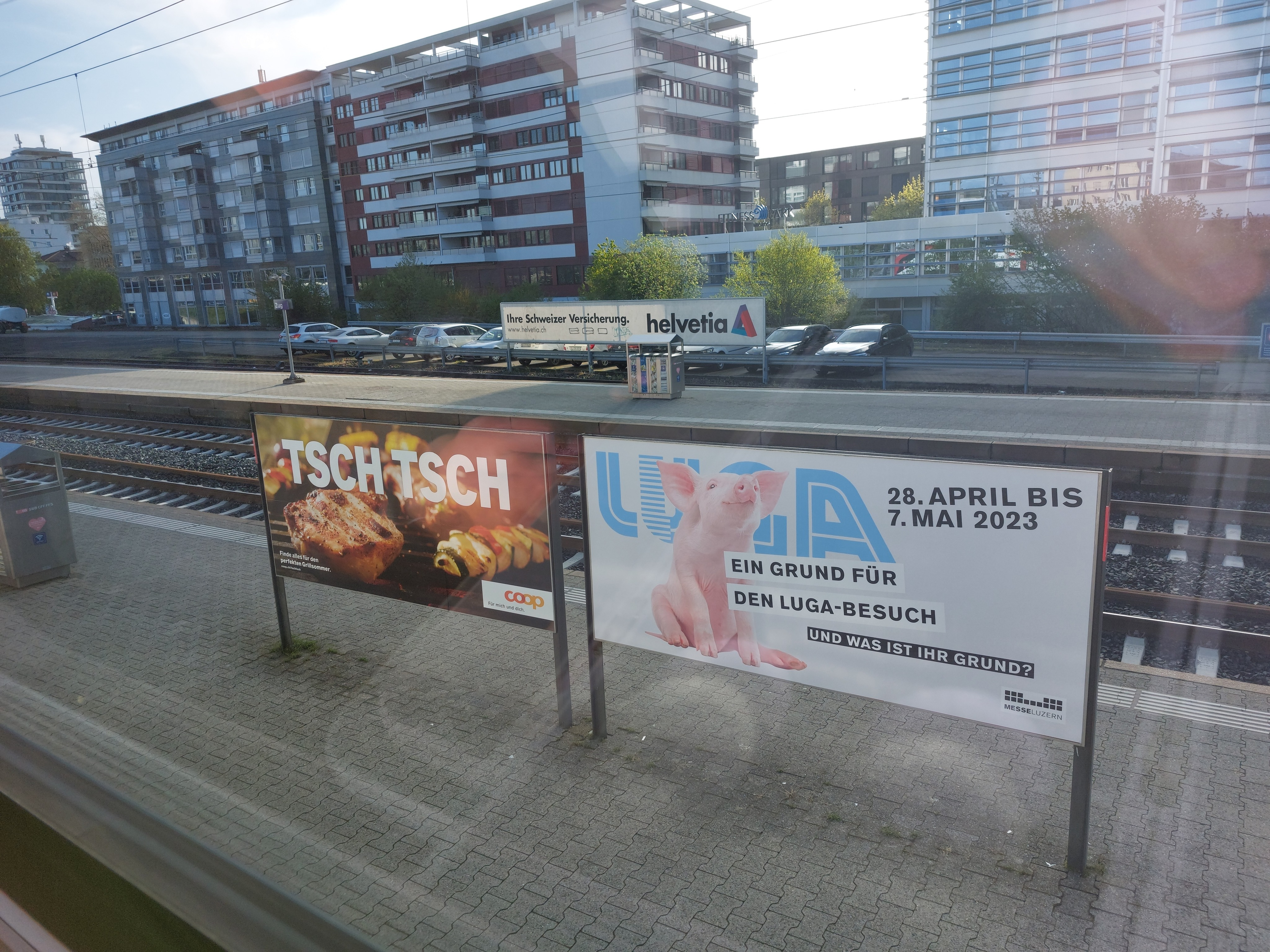 Two ads at the train station, one advertising a market with a cute piglet, the other showing two cuts of pork on a bbq with hissing noises